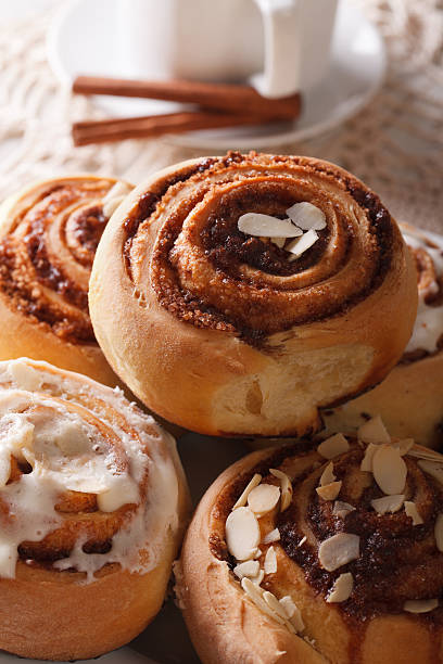 Freshly baked cinnamon rolls with icing and almonds macro on a plate